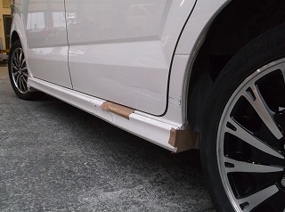 修理前のホンダ N-BOXの左側面下部。左後輪付近のステップモール（サイドスポイラー）が激しく破損して一部が欠損し、ガムテープのようなもので応急処置されている状態。