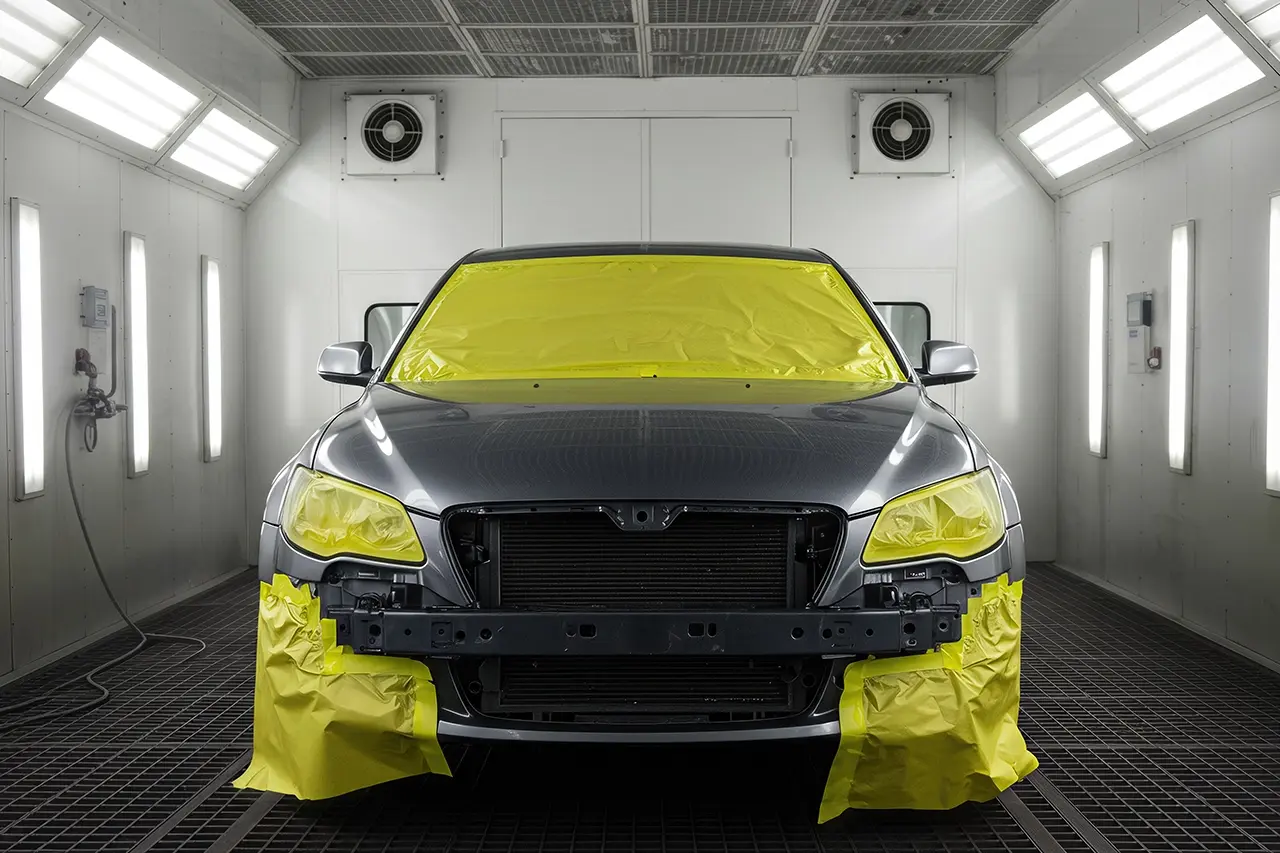 塗装ブースでマスキング作業がされた乗用車