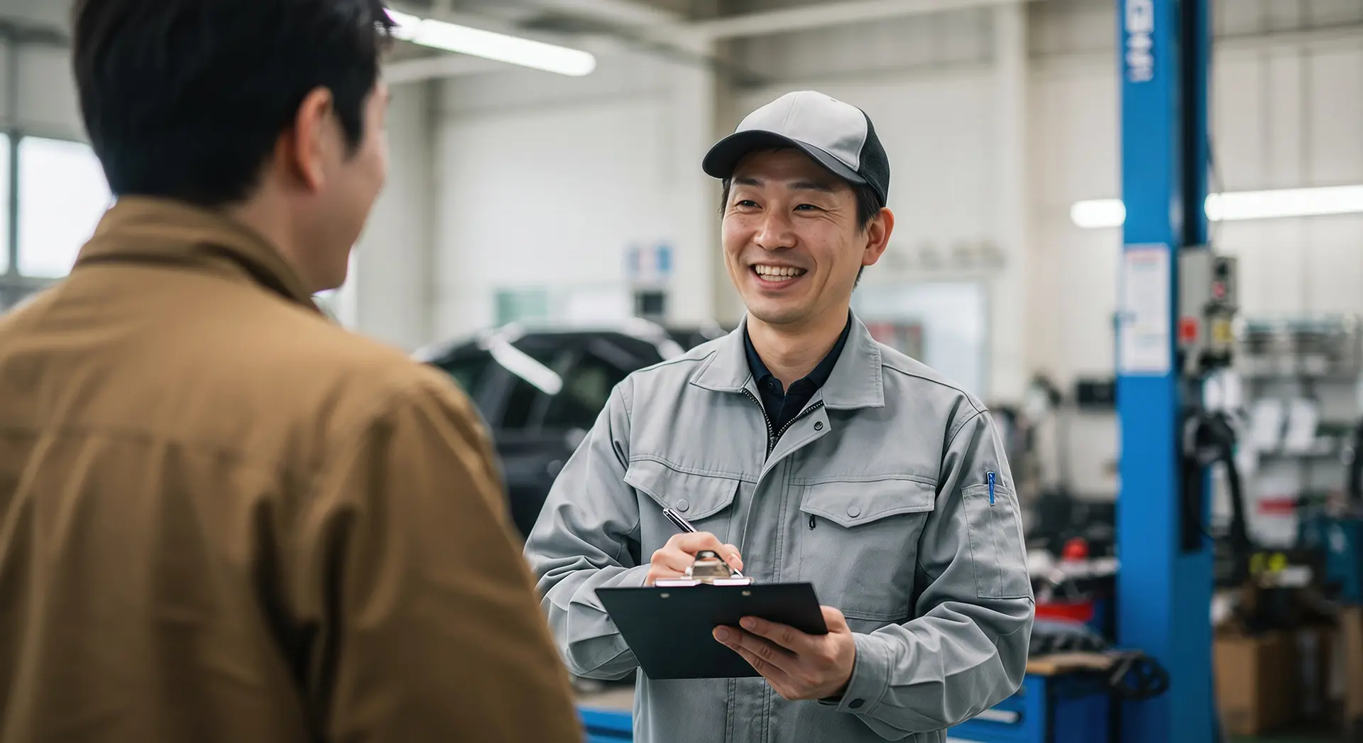 顧客と笑顔で話す自動車整備士